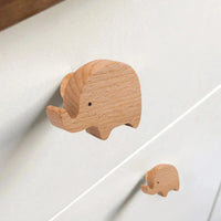 Twee lichte houten Bambino Olifantenknoppen van yessential.nl, een grote en een kleine, zijn bevestigd aan een witte lade. Hun speelse ontwerp voegt een minimalistisch tintje toe - perfect als accenten in de kinderkamer.