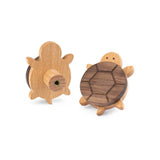 De Bambino Turtle meubelknoppen van yessential.nl zijn houten schildpadknoppen met donkere deken en lichte kop en poten, ideaal voor de kinderkamer. Eén knop toont de voorkant, de andere de achterkant met schroefbevestiging.