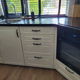 De Alvaro Black keuken van yessential.nl heeft witte kastjes, antraciet grijze afwerking, een ingebouwde oven, roestvrijstalen gootsteen, zwart aanrechtblad, klassieke handgrepen en ramen boven het aanrecht voor natuurlijk licht.