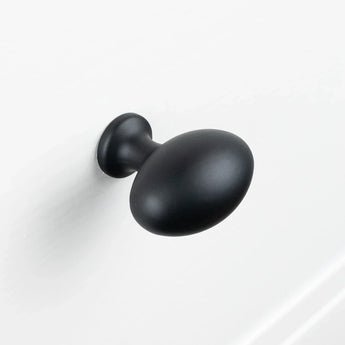 Een matzwarte, ovaalvormige Agero Black Knob Deluxe van yessential.nl is gemonteerd op een wit oppervlak.