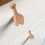 Twee Bambino Giraffe houten ladeknoppen van yessential.nl zijn bevestigd aan een witte commode en voegen een speels en uniek accent toe - perfect voor een kinderkamer of als opvallende dierenknoppen.