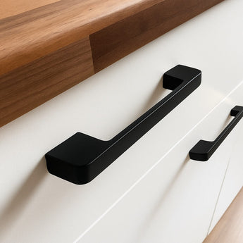 Close-up van de Ramiro Black Deluxe handgrepen van yessential.nl op een witte kast met een houten aanrechtblad. Deze luxe handgrepen verheffen het minimalistische en eigentijdse ontwerp.