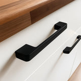 Close-up van de Ramiro Black Deluxe handgrepen van yessential.nl op een witte kast met een houten aanrechtblad. Deze luxe handgrepen verheffen het minimalistische en eigentijdse ontwerp.