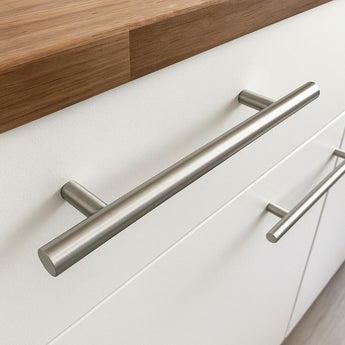 Close-up van Remo RVS handgrepen van yessential.nl op witte lades onder een houten aanrechtblad, voor een strakke en functionele afwerking.