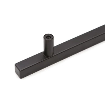 Een close-up van de Marano Black kastgreep van yessential.nl, met een moderne vierkante staaf en cilindrische paal, perfect voor minimalistische handgrepen, tegen een effen witte achtergrond.
