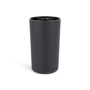 De Sicco Black 10cm van yessential.nl is een zwarte cilindrische beker met een matte afwerking en een rand met een kruispatroon. De beker staat rechtop op een witte achtergrond en weerspiegelt de strakke stijl van zwarte ronde meubelpootjes.