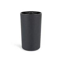 De Sicco Black 10cm van yessential.nl is een zwarte cilindrische beker met een matte afwerking en een rand met een kruispatroon. De beker staat rechtop op een witte achtergrond en weerspiegelt de strakke stijl van zwarte ronde meubelpootjes.