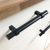 Een close-up van de Arturo Black handgreep van yessential.nl in matzwarte afwerking, gemonteerd op een lichte kast met houten blad. Op de achtergrond is nog eenzelfde handgreep zichtbaar.