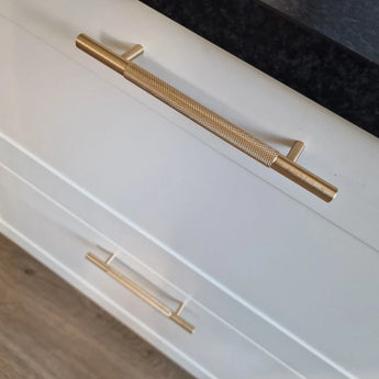 Close-up van twee Remo Gold Deluxe lades van yessential.nl, met elegante gouden handgrepen, tegen een donker aanrechtblad en een lichte houten vloer.