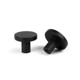 Twee Marizo Black meubelknopjes van yessential.nl, met een minimalistisch ontwerp en matte afwerking, worden getoond op een witte achtergrond - één rechtop en één op zijn kant, waarbij zowel het bovenaanzicht als het zijaanzicht zichtbaar zijn.