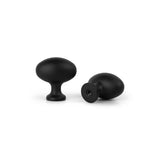 Twee Agero Black Knob Deluxe van yessential.nl zijn afgebeeld op een witte achtergrond: de ene staat rechtop, de andere ligt op zijn kant met een gat in de platte voet. Beide knoppen hebben een matzwart, paddestoelvormig ontwerp.