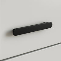 Een close-up van de Arriero Black Deluxe, een matzwarte, afgeronde rechthoekige handgreep van yessential.nl, bevestigd aan een glad wit ladefront-een modern voorbeeld van stijlvolle handgrepen.