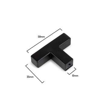 De Vigio Black Knob van yessential.nl is een moderne, T-vormige meubelknop (50mm breed, 35mm hoog, 12mm dik), afgebeeld op een witte achtergrond. Onderdeel van de Vigio collectie en ideaal als eigentijdse kastgreep.