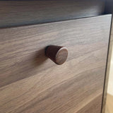 Close-up van een Salgado Walnut knop van yessential.nl op een houten lade. De gladde, bruine massief walnoothout afwerking wordt gedeeltelijk verlicht door natuurlijk licht van rechts.