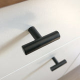 Close-up van een Remo Black knop van yessential.nl op een witte lade, met daaronder nog een identieke knop. De hoek benadrukt het moderne, minimalistische ontwerp van dit strakke beslag.