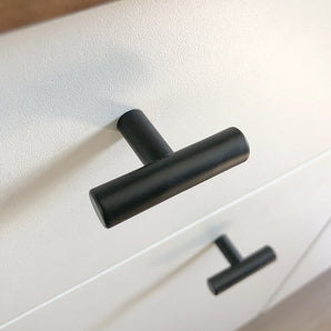 Nahaufnahme eines Remo Black-Knopfes von yessential.de auf einer weißen Schublade, mit einem weiteren identischen Knopf darunter. Die Ecke unterstreicht das moderne, minimalistische Design dieser schlichten Armatur.