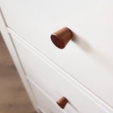Close-up van een lichtgekleurde kast met Salgado Walnut knoppen van yessential.nl. De focus ligt op de bovenste ronde knop, met een andere eronder. 