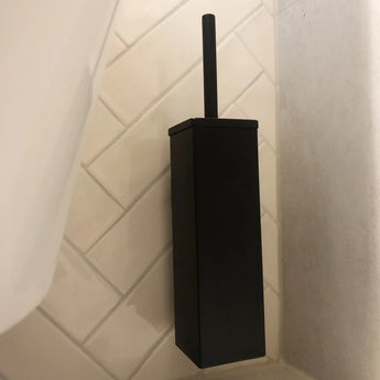 De Venzo Black WC set van yessential.nl, met een moderne rechthoekige houder en vierkant design, is geplaatst op een witte diagonale tegelvloer in een badkamerhoek.