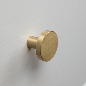 De Marizo Gold ronde knop van geborsteld messing van yessential.nl wordt gemonteerd op een lichtgrijs of wit vlak oppervlak en brengt elegante verfijning in elke ruimte.