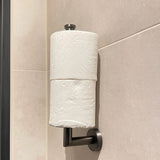 De yessential.nl Roberto Gunmetal is een toiletrolhouder voor wandmontage met twee rollen verticaal gestapeld op een metalen staaf, die een modern tintje geeft tegen beige betegelde muren.