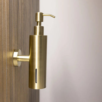 De Alberto Gold zeeppomp van yessential.nl met RVS muurbevestiging en verticale venstersleuf is bevestigd aan een houten wand, tegen een neutrale achtergrond.