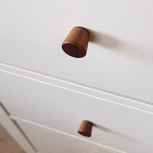 Close-up van twee Salgado Walnut Knobs van yessential.nl op een witte kast, met één knop scherp in beeld en de andere zachtjes onscherp op de achtergrond.