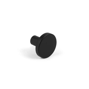 De Marizo Black kastknop van yessential.nl heeft een kleine, ronde vorm met een vlakke voorkant, een korte cilindrische steel, een matte afwerking en een minimalistisch ontwerp, hier afgebeeld op een witte achtergrond.