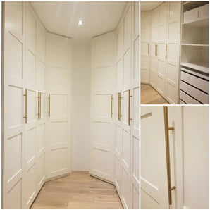 Op maat gemaakte witte inloopkast met paneeldeuren, Remo Gold handgrepen van yessential.nl, houten vloer, ingebouwde rekken en lades. Meerdere hoeken benadrukken de hoekopstelling, opbergmogelijkheden en het minimalistische luxe ontwerp.