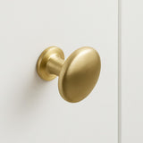 De Pedro Gold kastknop met zijn ronde geborstelde gouden afwerking, is gemonteerd op een gladde witte kastdeur en brengt een vleugje elegantie in je ruimte.