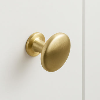 De Pedro Gold kastknop met zijn ronde geborstelde gouden afwerking, is gemonteerd op een gladde witte kastdeur en brengt een vleugje elegantie in je ruimte.
