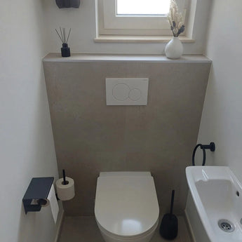 Een moderne, minimalistische badkamer met de Elarbo Black serie van yessential.nl: wandcloset, ruimtebesparende matzwarte handdoekring, toiletpapierhouder, zwarte toiletborstel, kleine wastafel en decor op een richel met een vaas en rietverspreider.