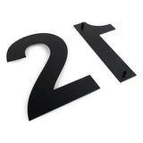 Twee grote Adamo Black 30cm RVS huisnummers van yessential.nl, 2 en 1, liggen op een witte ondergrond. Het cijfer 1 ligt plat met zichtbare bevestigingspinnen, wat zorgt voor een zwevend effect.