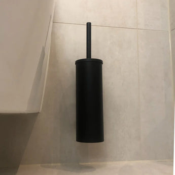 Een Nando Black WC-set van yessential.nl is gemonteerd op een lichtbeige betegelde badkamermuur, naast de rand van een wit toilet.