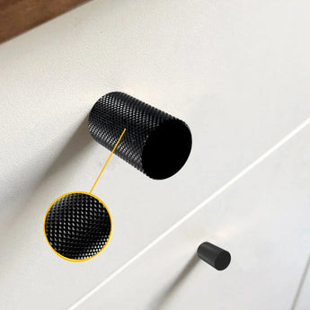 Een close-up van een Remo Black Deluxe knop van yessential.nl op een witte kast, met een inzet die het gedetailleerde gekartelde oppervlak van de moderne knop benadrukt.