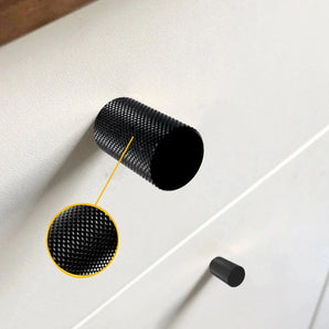Een close-up van een Remo Black Deluxe knop van yessential.nl op een witte kast, met een inzet die het gedetailleerde gekartelde oppervlak van de moderne knop benadrukt.