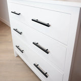 Het Marano Black dressoir van yessential.nl heeft drie witte lades met minimalistische zwarte handgrepen, op een lichte houten vloer tegen een witte muur.