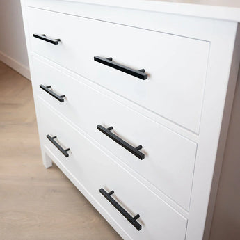 Het Marano Black dressoir van yessential.nl heeft drie witte lades met minimalistische zwarte handgrepen, op een lichte houten vloer tegen een witte muur.