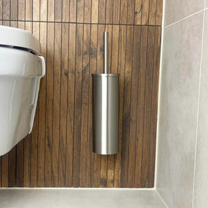 De Lorenzo RVS WC set van yessential.nl heeft een roestvrijstalen toiletborstelgarnituur gemonteerd op een houten latten wand naast een wit toilet, die de look van je moderne badkamer verfraait met stijlvolle RVS badkameraccessoires.
