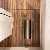 Een moderne badkamer met de Xavo Gunmetal WC-set van yessential.nl - een wandgemonteerde roestvrijstalen toiletborstelhouder - tegen een verticale houten lambrisering naast een wit toilet. Perfect om je badkamer te moderniseren.