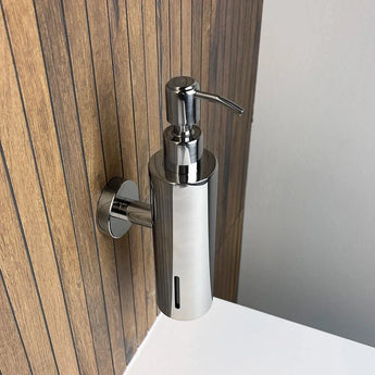 De Alberto Chrome zeeppomp van yessential.nl is aan de muur boven een witte wastafel gemonteerd en geeft de houtgepaneelde badkamer een moderne uitstraling.