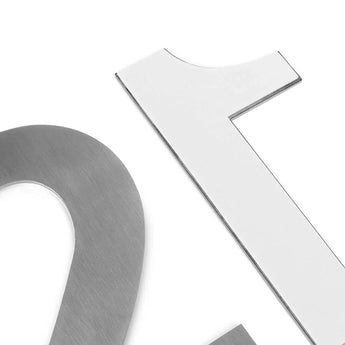 Close-up van metallic en witte uitgesneden nummers op een witte achtergrond, met gedeeltelijke weergaven van Animo RVS 15cm (geen boor) van yessential.nl in zilver en wit.