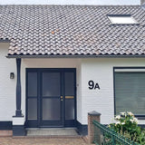 Een huis met een raam en een deur, voorzien van Animo Black 20cm (niet boren) huisnummer voor eenvoudige, zelfklevende installatie.