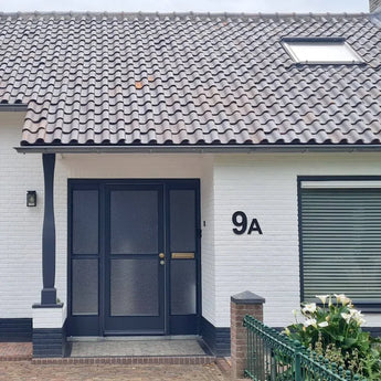 Een huis met een raam en een deur, voorzien van Animo Black 20cm (niet boren) huisnummer voor eenvoudige, zelfklevende installatie.