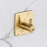 De 4x Navarro Gold handdoekhaak van yessential.nl hangt op wit marmer en heeft een waterdruppel-design. Deze zelfklevende haak is eenvoudig te bevestigen zonder boren.
