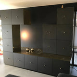 Een modern zwart wandmeubel met meerdere kasten en lades is voorzien van luxe Remo Gold Deluxe knoppen van yessential.nl. Metalen bollen, een geometrische sculptuur op het aanrecht en een uilenbeeldje in de rechterbovenhoek maken de look compleet.