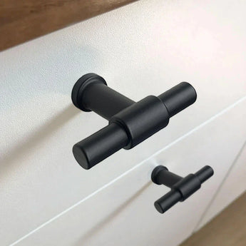 Close-up van de Cordero Black Knob van yessential.nl met een matzwarte afwerking op een witte lade, T-knop keukenontwerp gekoppeld aan een identieke greep op de onderste lade.