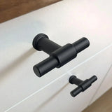 Close-up van de Cordero Black Knob van yessential.nl met een matzwarte afwerking op een witte lade, T-knop keukenontwerp gekoppeld aan een identieke greep op de onderste lade.