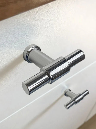 Close-up van de 10x Cordero Chroom knop van yessential.nl, gemonteerd op een witte kast - de ene knop is scherp, de andere onscherp. Een ideale keuze voor moderne interieurs die op zoek zijn naar stijlvolle chromen meubelknoppen.