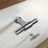 Close-up van de 10x Cordero Chroom knop van yessential.nl, gemonteerd op een witte kast - de ene knop is scherp, de andere onscherp. Een ideale keuze voor moderne interieurs die op zoek zijn naar stijlvolle chromen meubelknoppen.