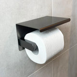 De Santino Gunmetal WC-set van yessential.nl heeft een strakke toiletpapierhouder met een plat bovenblad, gemonteerd op grijze tegels - ideaal voor iedereen die de badkamer in stijl wil moderniseren.